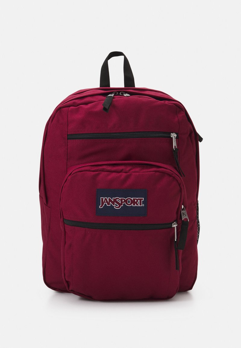 Crvena Jansport ruksak s dva patentna prednja džepa, podstavljenim naramenicama i ručkom na vrhu za nošenje. Čvrst materijal.