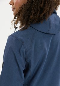 Tummansininen huppari, joka on valmistettu tekstuuri kankaasta. Varustettu korkealla kauluksella ja hienolla ompelulla. Sisältää logon hihassa.