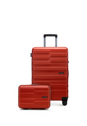 Valigia rigida rossa con manico telescopico e valigia più piccola abbinata, entrambe con scanalature orizzontali e ruote nere.