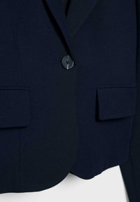 Blazer ajusté bleu marine avec deux poches avant, fermeture à un bouton, et texture de tissu lisse, présentant des détails de couture subtils.
