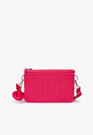 Petit sac bandoulière rose vif avec "LOVE" brodé sur le devant et un porte-clés en forme de singe en peluche attaché à la sangle.