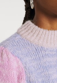 Stickad tröja med en pastellfärgad palett i rosa, lavendel och ljusblå nyanser. Strukturerad tyg och details med ribbad krage.