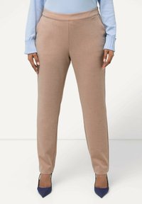 Pantaloni beige su misura con una texture liscia, design affusolato e vita alta intermedia, abbinati a tacchi a punta blu navy.
