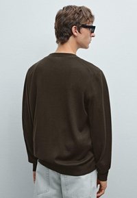 Mörkbrun stickad sweatshirt med rund halsringning, långa ärmar och avslappnad passform. Slät textur, enkel design, inga synliga mönster.
