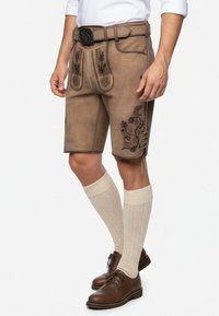 Bruine leren lederhosen shorts met geborduurde motieven, een leren riem en knie-lange gebreide sokken in combinatie met bruine schoenen.