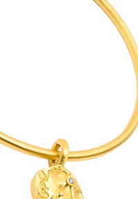 Złoty bransoletka z gładkim, zaokrąglonym paskiem i teksturowanym charms'em przedstawiającym symbol Koziorożca oraz małym diamentowym akcentem.
