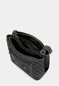 Bolso de mano de piel acolchada en gris con herrajes dorados, que cuenta con un cierre de cremallera y múltiples compartimentos interiores para un almacenamiento organizado.