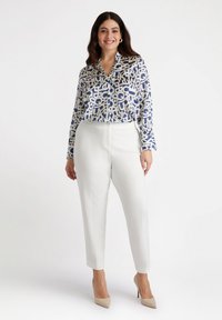 White tailored trousers paired with a blue patterned blouse featuring abstract designs. The blouse has a collar and long sleeves.