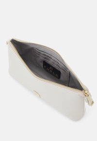 Bílá kožená taštička na zip se zlatým zipem a logem Furla, ukazuje šedou látkovou podšívku s přihrádkami na karty uvnitř.