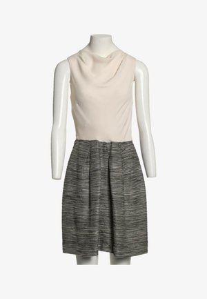 Robe sans manches avec haut col bénitier crème et jupe plissée à rayures noires et blanches taille haute sur un mannequin blanc.
