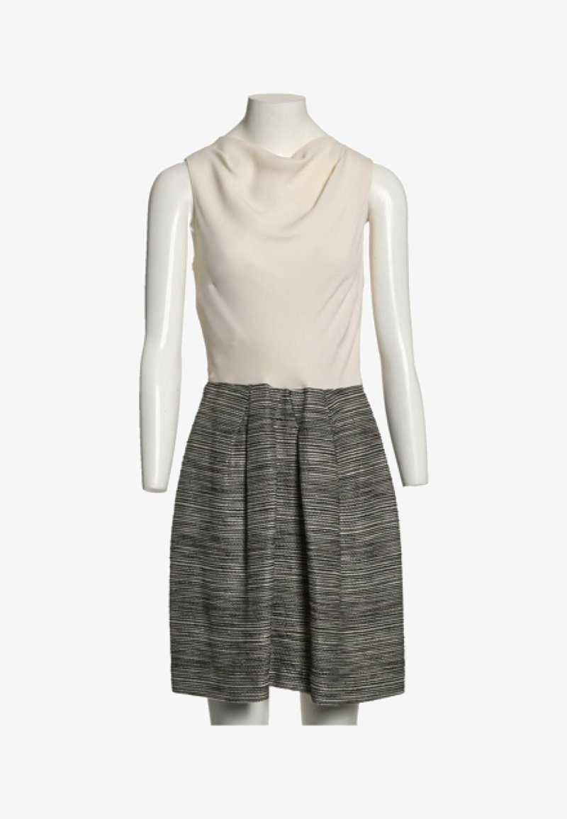 Robe sans manches avec haut col bénitier crème et jupe plissée à rayures noires et blanches taille haute sur un mannequin blanc.