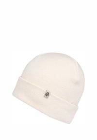 Cream-colored knit beanie with a cuffed design and a small branded metal tag on the front. Soft texture and rounded top.