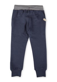 Marineblaue Jogginghosen mit einem gestreiften Bund, schmal zulaufendem Bein, weichem Material und einem kleinen Markenschild auf der Rückseite.