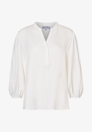 Blouse blanche en tissu doux avec un décolleté en V, une patte de boutonnage et des manches volumineuses froncées aux poignets. Texture lisse.