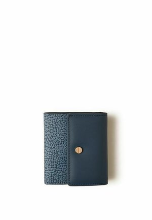 Portefeuille compact bleu foncé avec tissu texturé sur un côté et cuir lisse avec une petite fermeture à bouton doré sur fond blanc.