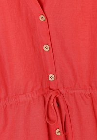 Robe en lin rouge avec une taille à cordon, des boutons en bois et une coupe décontractée. La texture semble légère et respirante.