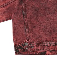 Giacca in denim rosso con una texture sbiadita, caratterizzata da bottoni a pressione sui polsini e dettagli neri. Il design presenta una finitura usurata.