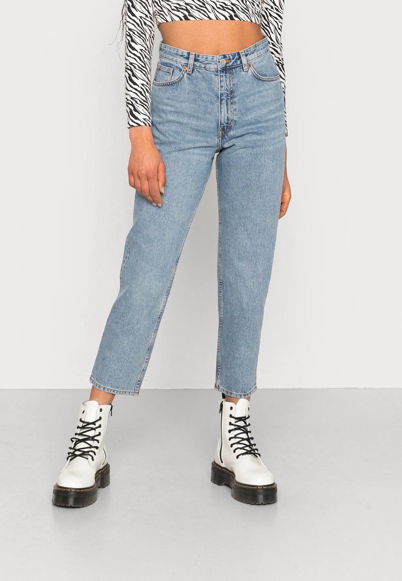 Lichtblauwe high-waisted denim jeans met een rechte leest, met vervaagde plekken en een cropped zoom, gecombineerd met witte veterschoenen.
