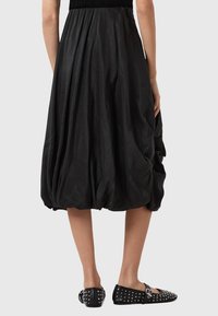Gonna nera a palloncino realizzata in tessuto leggero con vita arricciata, caratterizzata da una texture morbida e una forma voluminosa e drappeggiata.