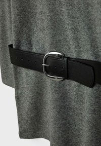 Šedý textilný odev s čiernym koženým opaskom, ktorý má lesklú striebornú pracku a viacero dierok na nastavenie, pričom zdôrazňuje textúru a farebný kontrast.