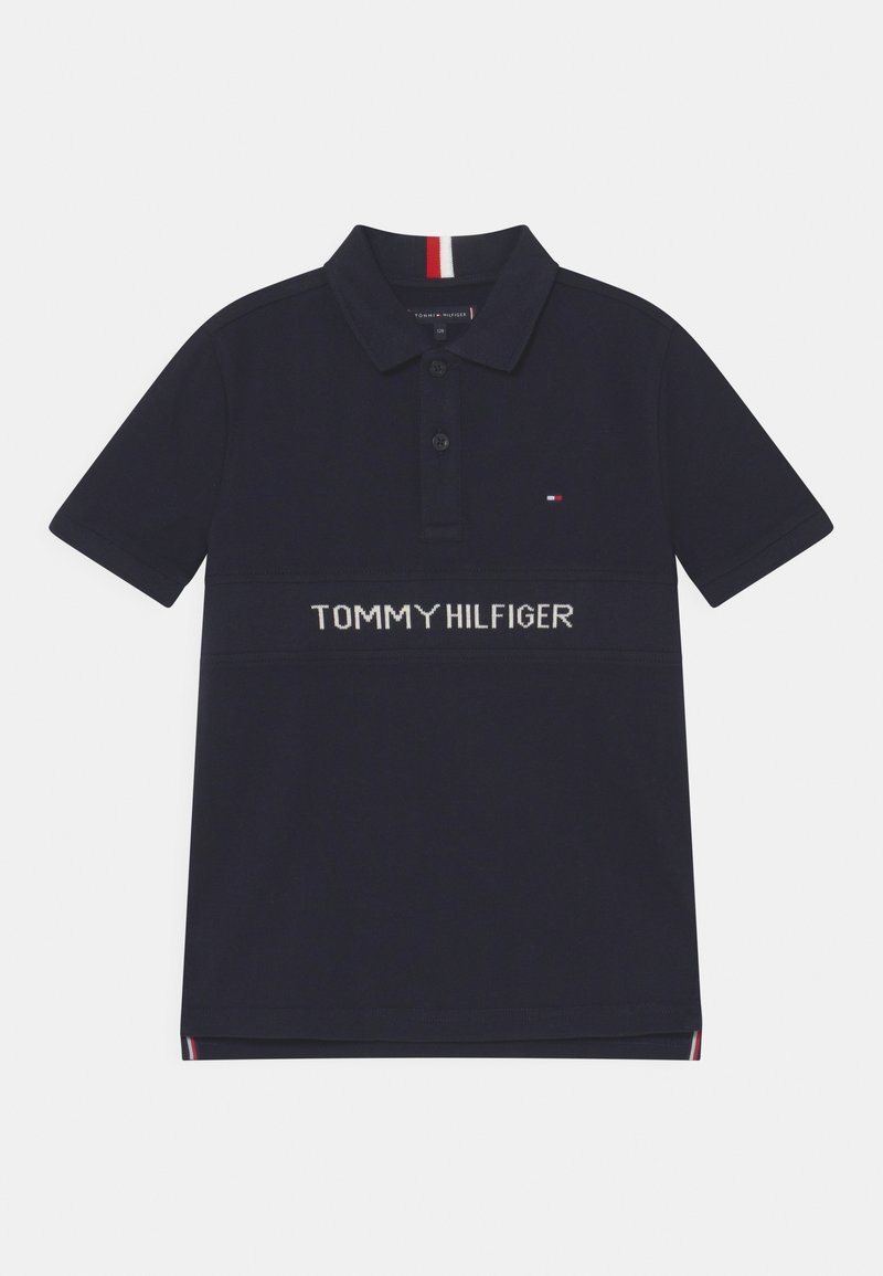 Polo bleu marine à manches courtes, patte de boutonnage à deux boutons, petit logo drapeau Tommy Hilfiger sur la poitrine et nom de la marque blanc sur le devant.
