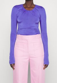 Fialový dlouhý rukáv top s nařaseným výstřihem a slim fit, spárovaný s vysokým pasem růžovými kalhotami s předními kapsami a texturovanou látkou.