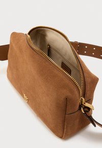 Καφέ τσάντα χειρός από σουέντ με χρυστό φερμουάρ, ευρύχωρο εσωτερικό και καφέ ρυθμιζόμενο λουράκι. Χωρίς εμφανή σχέδια ή πρόσθετα μεταλλικά μέρη.