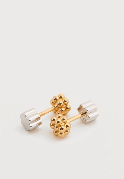 Σκουλαρίκια καρφάκια σε σχήμα χρυσού λουλουδιού με λείες ασημένιες πλάτες σε λευκή επιφάνεια.