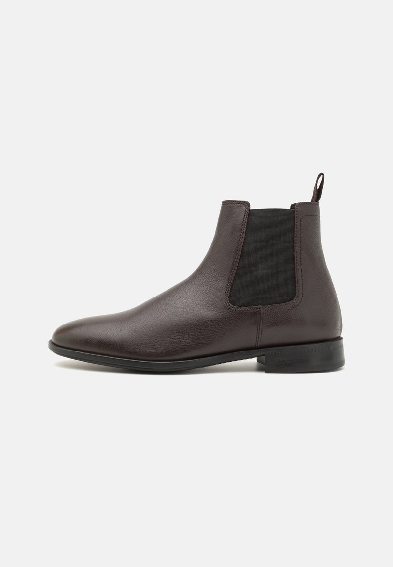 Brązowy skórzany botek Chelsea z elastycznymi panelami bocznymi, niskim obcasem i gładką fakturą; pętelka z tyłu ułatwiająca zakładanie.
