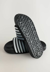 Șlapi negri și gri cu dungi orizontale, material cauciucat texturat și model de tip chevron pe talpă pentru aderență.