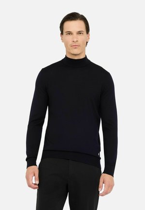 Maglione a collo alto navy in morbido tessuto a maglia fine. Vestibilità slim con maniche lunghe e orli a coste, abbinato a pantaloni neri.