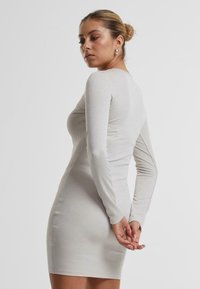 Sølv langtermet bodycon kjole med en glitrende tekstur, kroppsnær silhuett og rund halslinje, som viser et enkelt og elegant design.
