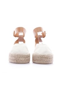 Espadrilles de lona blanca con suela de yute, que cuentan con una correa de tobillo marrón y un respaldo transparente para un ajuste seguro.