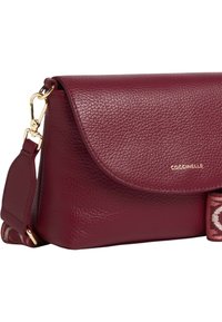 Bordowa skórzana torba na ramię z fakturowanym wykończeniem, złotymi okuciami i wzorzystym paskiem z tkaniny. Wyposażona w magnetyczne zapięcie na klapę.