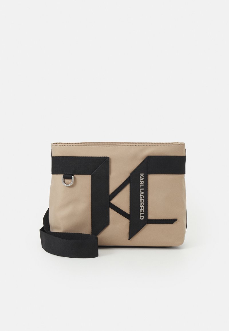 Borsa in nylon beige con accenti in tessuto nero e logo 'Karl Lagerfeld'. Presenta una chiusura con zip e una tracolla rimovibile. Forma rettangolare.
