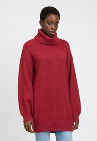 Rød, oversized turtleneck sweater med lange, brede ærmer, lavet af blødt, tekstureret stof. Simpelt design, uden mønstre eller pynt.