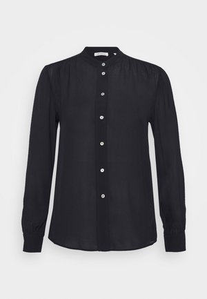 Sort bluse med lange ærmer, høj krave, knaplukning foran og diskrete rynkedetaljer ved skuldre og manchetter.