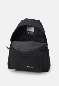 Černý batoh s zipovou přední kapsou, nastavitelnými popruhy a prostorným vnitřkem. Obsahuje logo značky a textilní štítek. Odolný materiál.