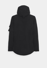 Černá kapucí bunda s dlouhými rukávy, texturovaná tkanina, zakřivený lem a malá kapsa na levém rameni.