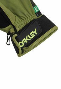 Guanto in pelle verde con polsino in tessuto nero, caratterizzato da un patch con logo e polso elastico per una vestibilità sicura. Dettagli di cucitura evidenti.