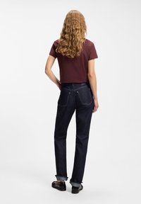 Μπορντό κοντομάνικη cropped μπλούζα, συνδυασμένη με σκούρα τζιν παντελόνια με ευθείς φάσες και γυρισμένα μανίκια. Μαύρα παπούτσια ολοκληρώνουν την εμφάνιση.