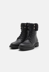 Black leather lace-up ankle boots with faux fur trim and gold eyelets, sturdy soles, designed for winter wear.