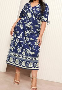 Tmavě modré květované midi šaty s krátkými rukávy, staženým pasem a světlým květinovým vzorem. Na lemu je ozdobná lemovka.