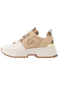 Baskets beige épaisses avec un logo doré, des accents texturés et des côtés blancs. Elles disposent de lacets marron, d'un dos à motif et d'une semelle en caoutchouc antidérapante.