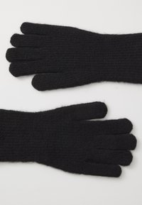 Guantes de lana negros con textura acanalada y diseño de cinco dedos, colocados en una superficie blanca.