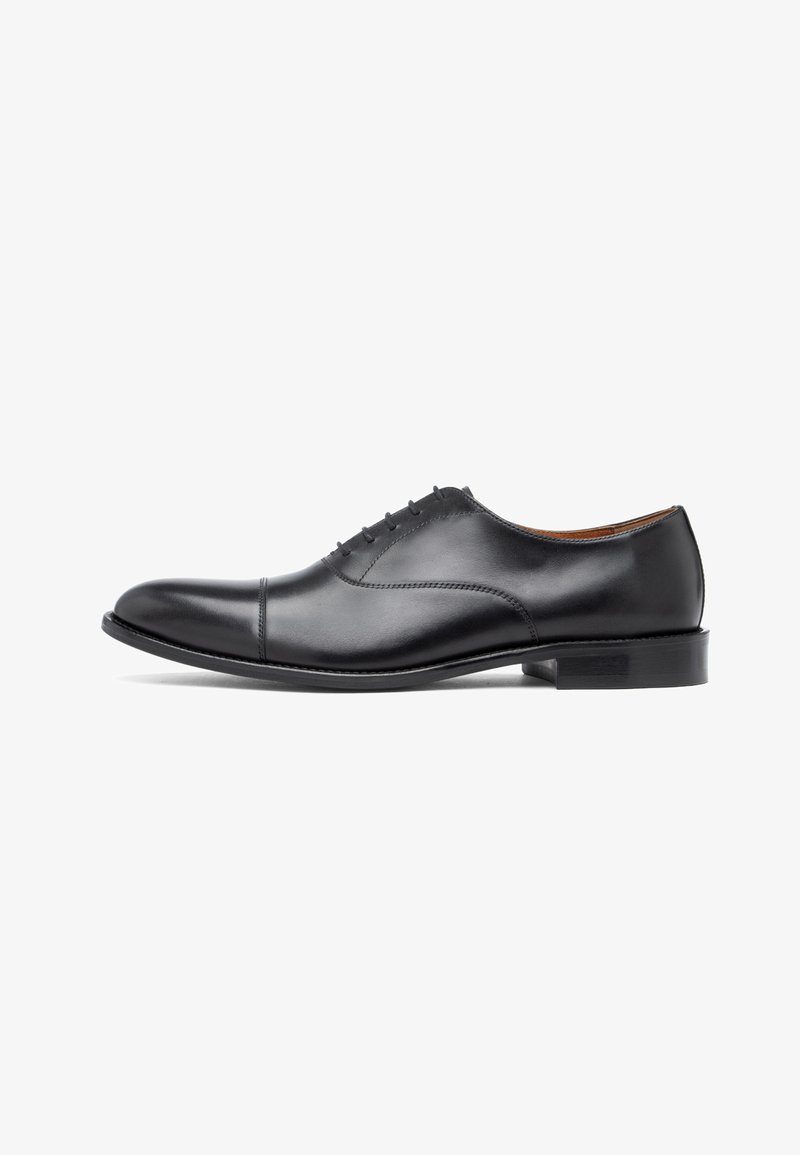 Chaussure habillée Oxford en cuir noir avec laçage fermé, bout droit et petit talon, présentée de profil sur fond blanc.