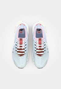 Baskets de sport bleu clair avec un mélange de matériaux en maille et synthétiques, des accents rouges, des côtés perforés et un design de semelle éclaboussée.