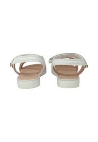Sandali bianchi con una parte superiore liscia in materiale sintetico, apertura sul retro e cinturino alla caviglia regolabile. Suola piatta con una soletta di un leggero color beige. Design semplice.