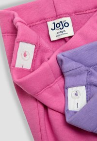 Två plagg: en rosa överdel och en lavendelfärgad underdel. Varje plagg har en etikett med märket "JoJo." Mjukt bomullstyg, enkel design.