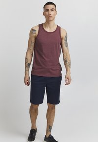 Bordeauxrotes Tanktop mit rundem Halsausschnitt, kombiniert mit navyblauen Shorts. Das Outfit zeichnet sich durch eine weiche Textur und ein lässiges Design aus, das sich für warmes Wetter eignet.